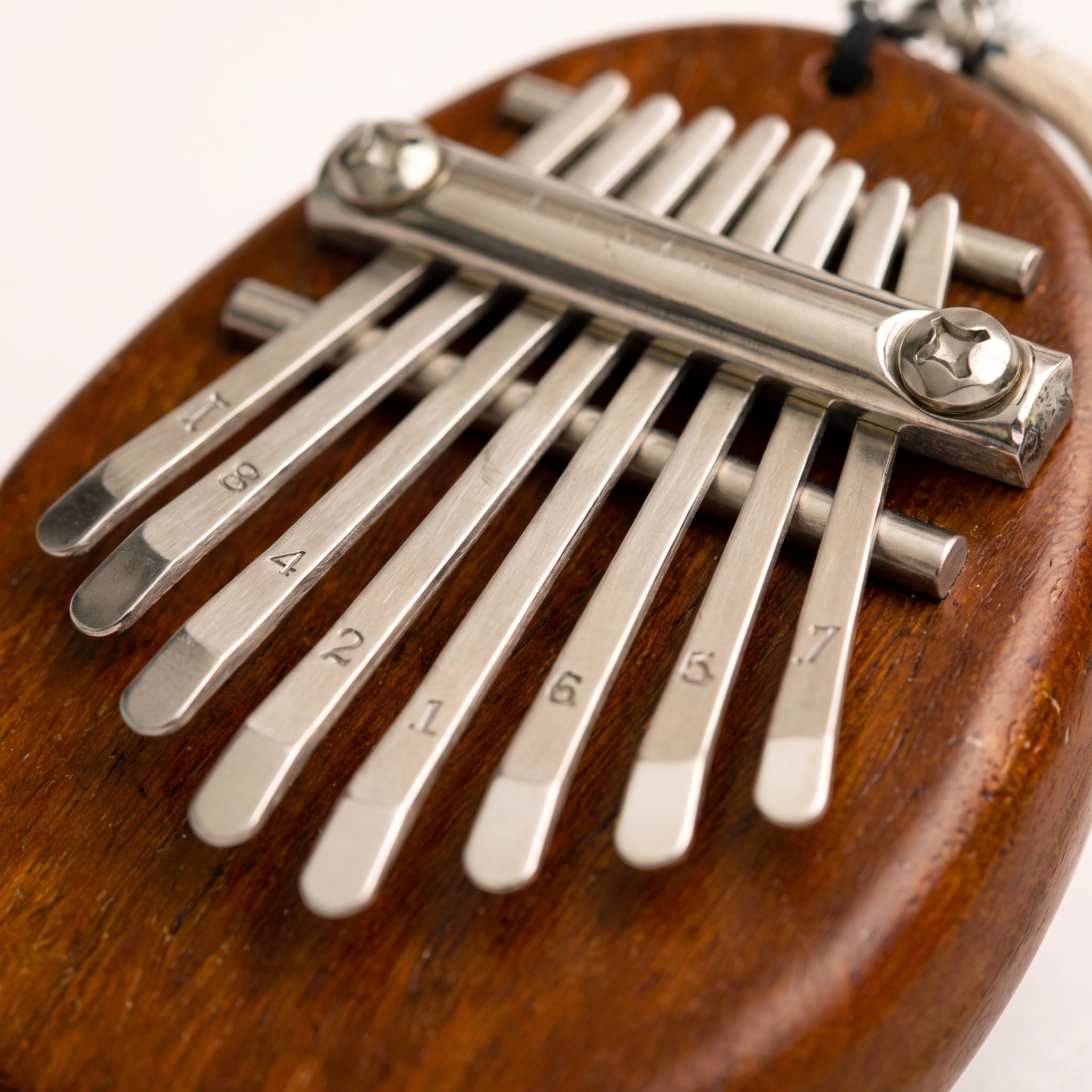A close-up of a wooden kalimba thumb piano with silver metal tines numbered 1 through 7, resting on a dark brown wooden surface.